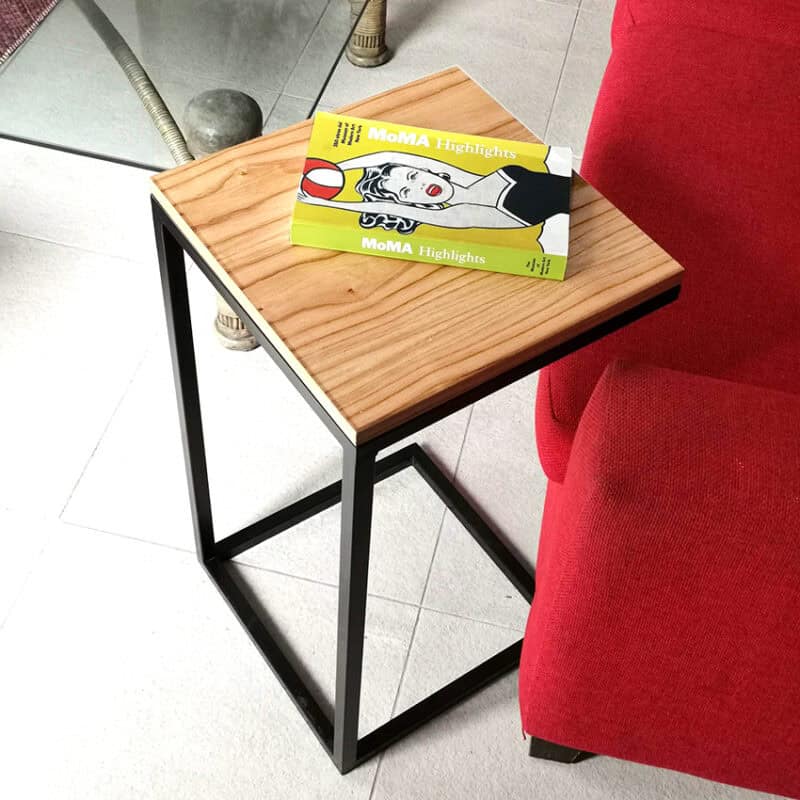 Mesa auxiliar de madera y metal en espacio contemporáneo con sillón rojo.