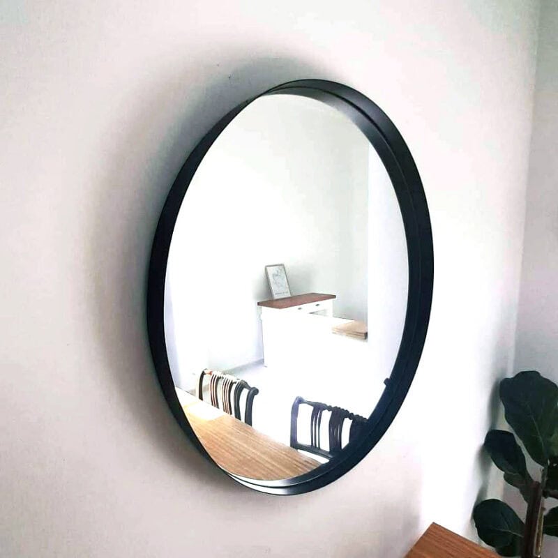Espejo ovalado de diseño moderno en pared blanca.