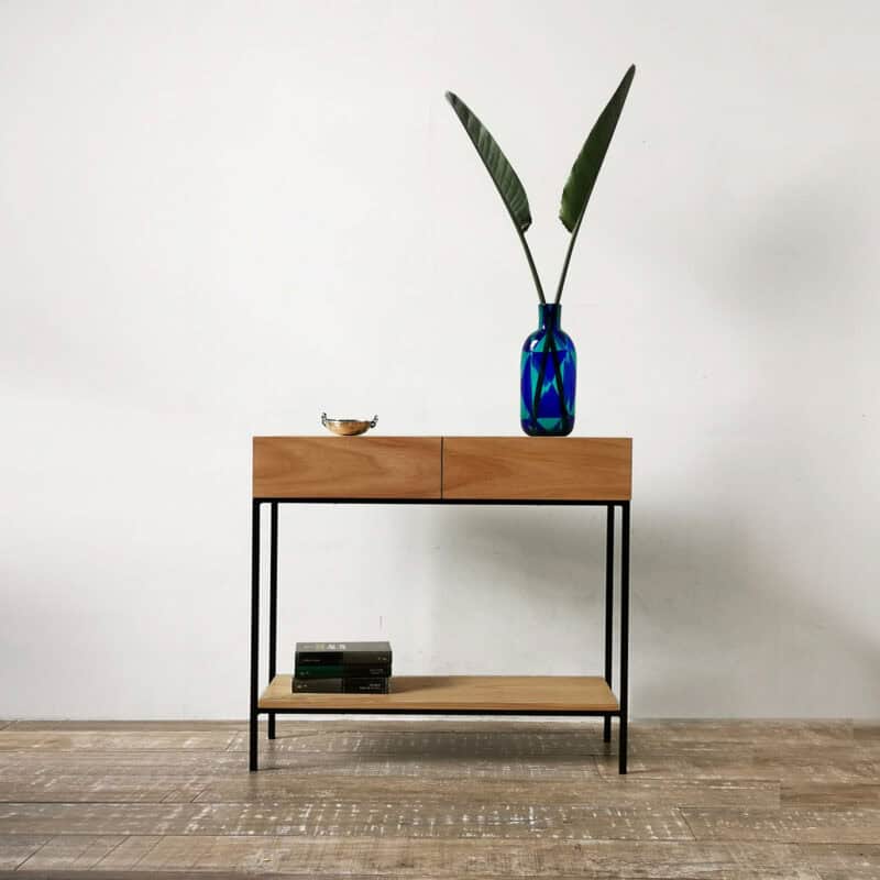 Consola minimalista con dos cajones de madera y estructura negra en ambiente moderno.