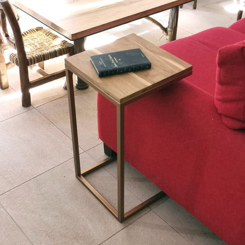 Mesa auxiliar de madera con estructura metálica en sala moderna.