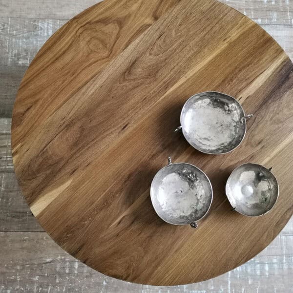 Mesa de madera natural con tres candelabros de metal en la superficie.