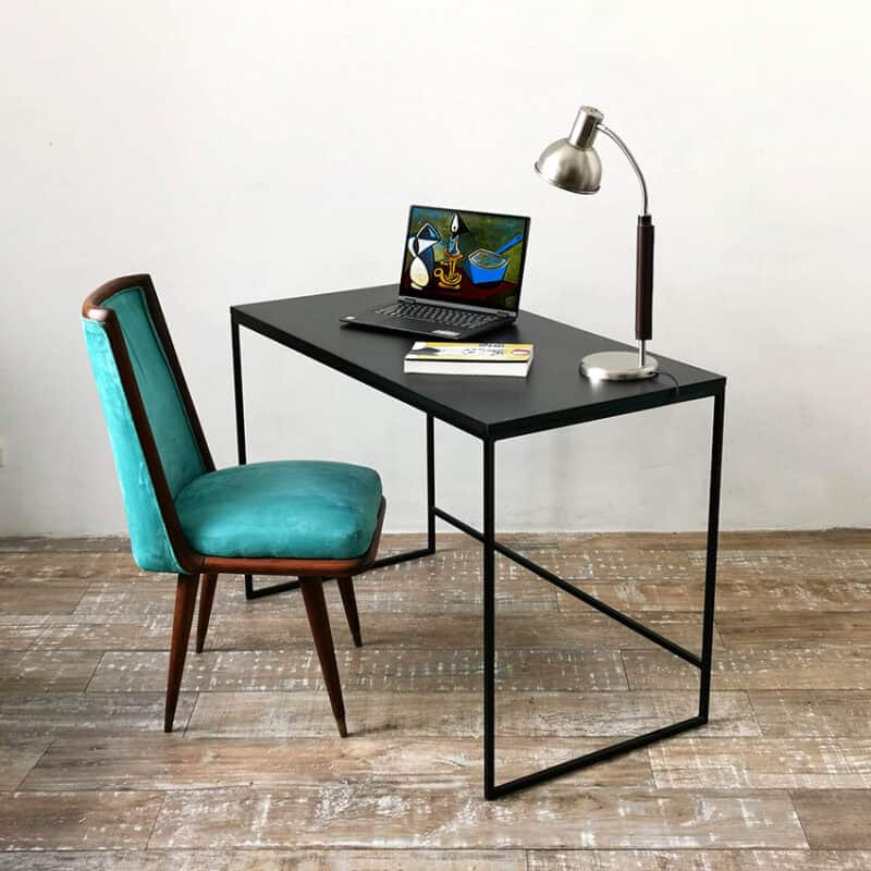 Escritorio negro con lámpara y computadora portátil en ambiente moderno.