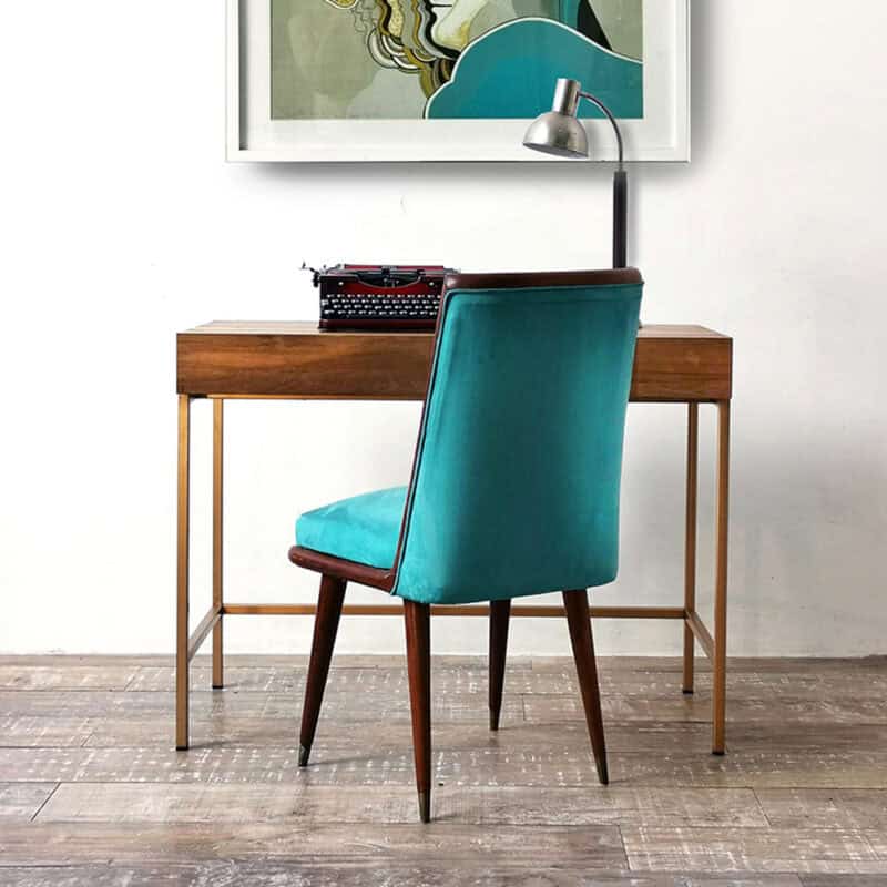 Escritorio de madera con silla azul y lámpara moderna en oficina.