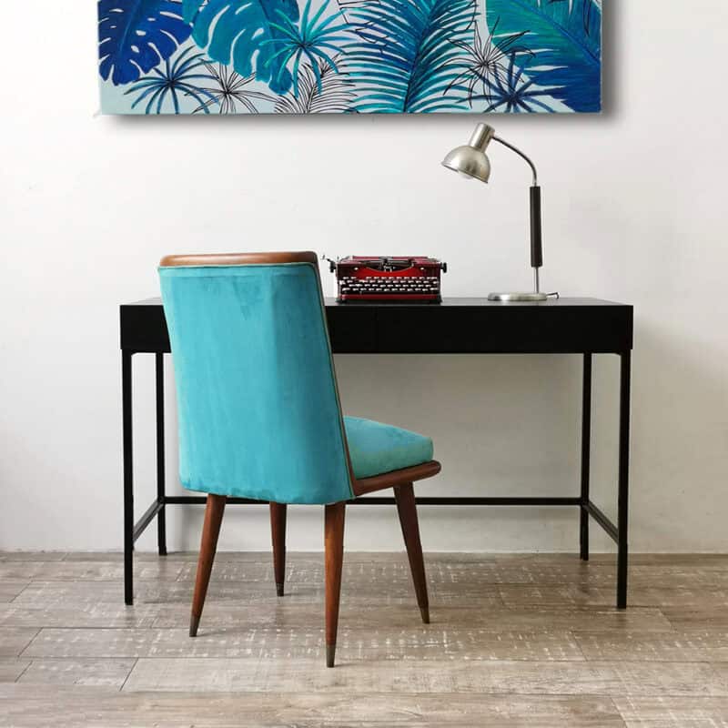 Escritorio negro con lámpara y silla azul en ambiente moderno.