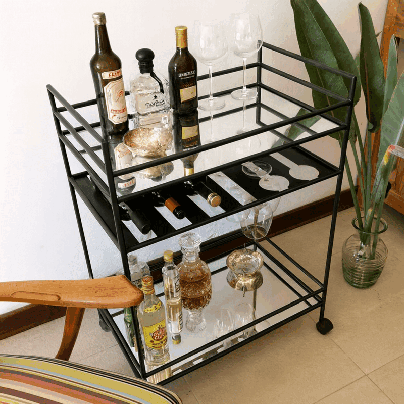 Carro bar negro con botellas y copas en decoración moderna.
